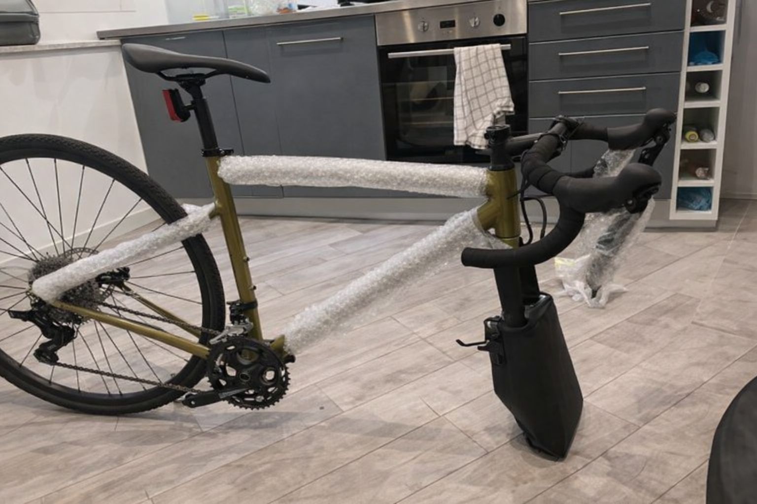 En guldgrön racercykel delvis skyddad med bubbelplast inför frakt.